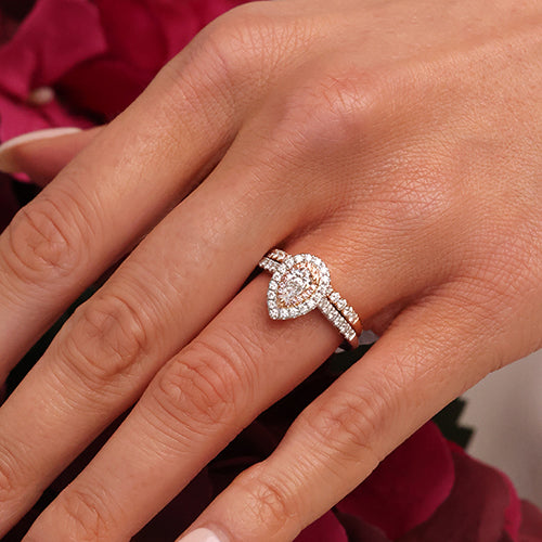 Hand with pear shaped engagement ring and diamond pave wedding band