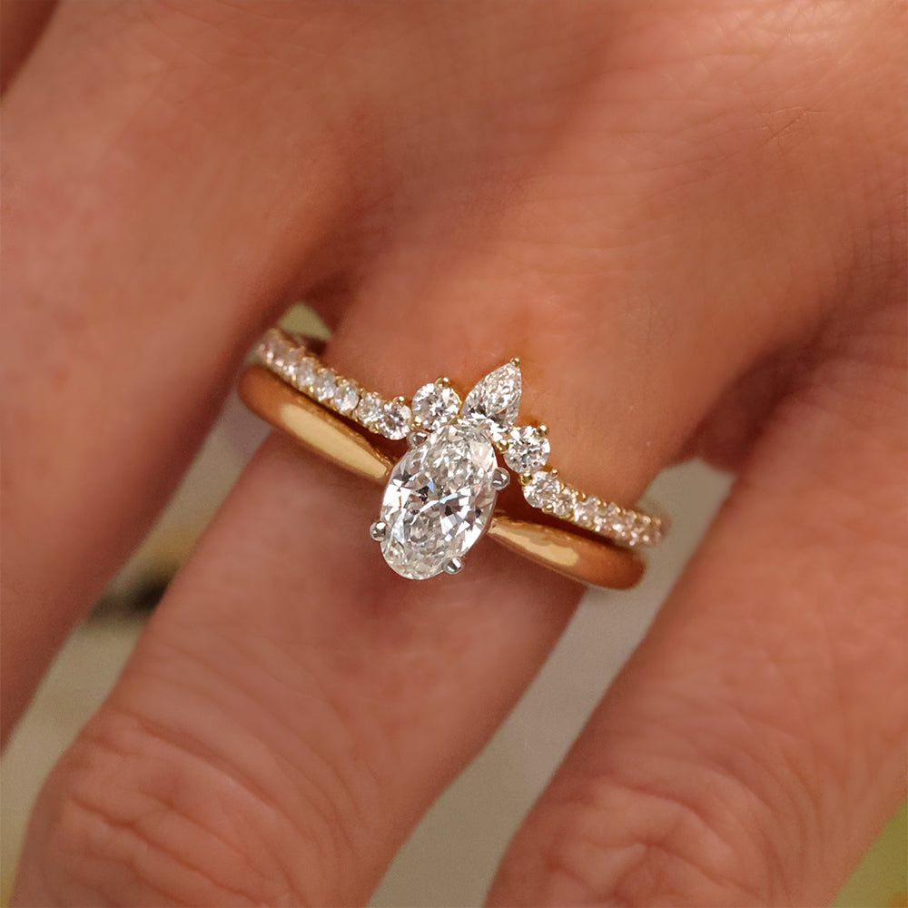 Close up of oval solitaire engagement ring with wedding band shaped around on hand